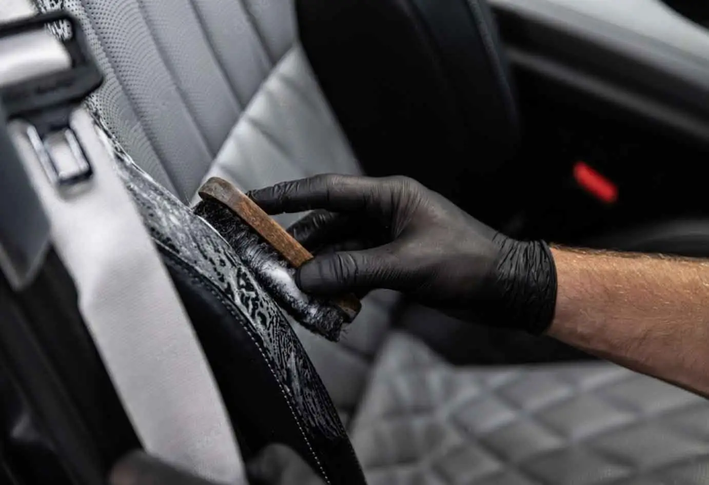 Detailer cleaning leather car seat with brush